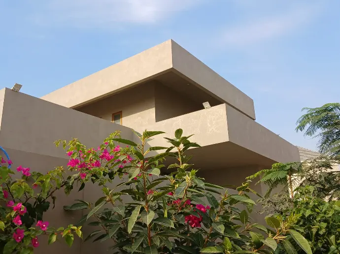 Cemplast on exterior surface CemPlast is applied over a building exterior, in sandy earth tone.The monolithic polished surface with a contrast of bougainvillea foliage at front, creates an impressive look.